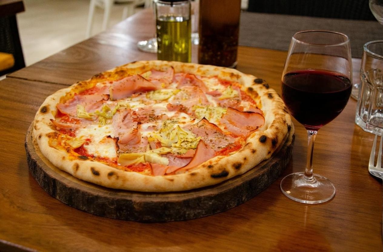 Wood-fired ham pizza with a glass of red wine at Pizza on Fire