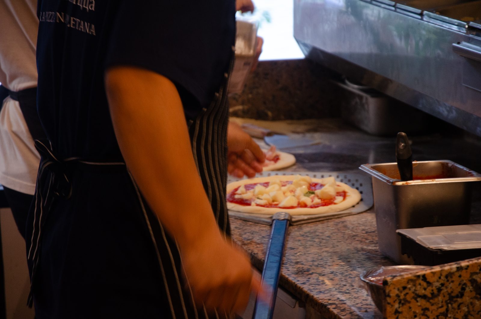 Pizzaiolo stretching pizza dough by hand at Pizza on Fire